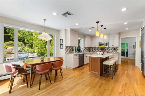a kitchen with stainless steel appliances a dining table chairs and wooden floor