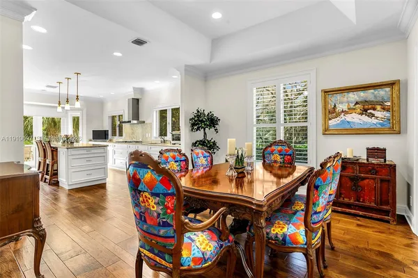 a view of a dining room with furniture one side kitchen view and wooden floor