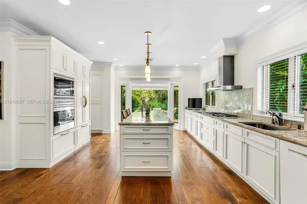 a kitchen with stainless steel appliances a kitchen island hardwood floor sink stove and wooden cabinets
