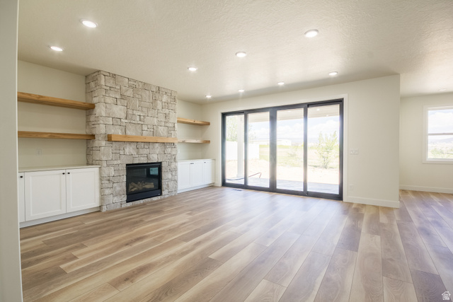 3322 250 S Street Vernal, UT 84078 - Photo 2 of 37 Stone-clad fireplace with a wood mantel and built-in shelving, complemented by wood-finish flooring