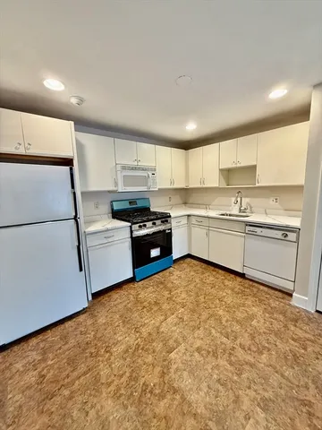 a kitchen with stainless steel appliances granite countertop a refrigerator sink and white cabinets