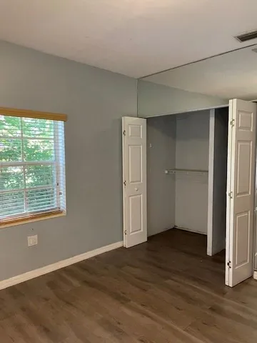 an empty room with wooden floor cabinet and windows