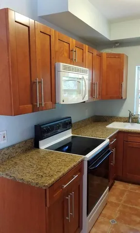 a kitchen with stainless steel appliances granite countertop a stove a sink and a microwave