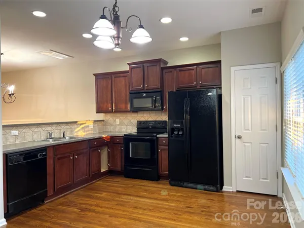 a kitchen with stainless steel appliances granite countertop wooden cabinets a refrigerator a sink a stove and dishwasher