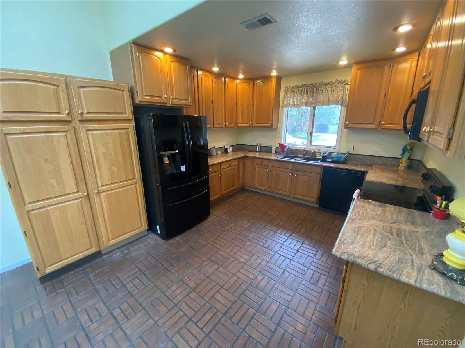 7079 Estes Drive Arvada, CO 80004 - Photo 17 of 50 a kitchen with granite countertop a refrigerator a sink and wooden floors