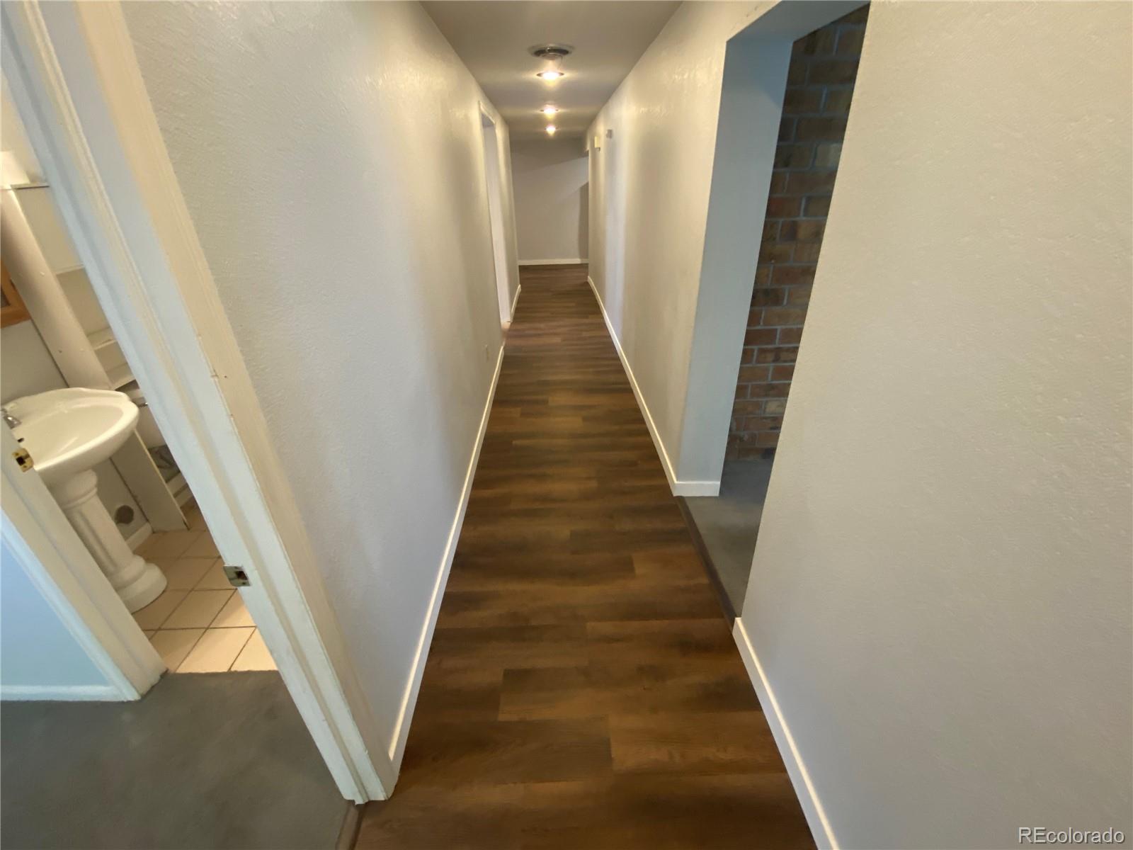 7079 Estes Drive Arvada, CO 80004 - Photo 44 of 50 a view of a hallway with wooden floor and staircase