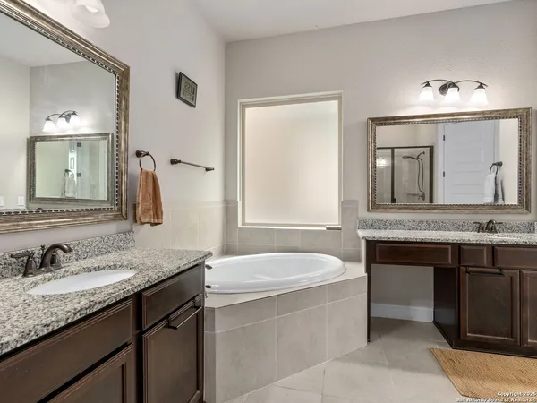 a bathroom with a granite countertop bathtub a sink and a mirror