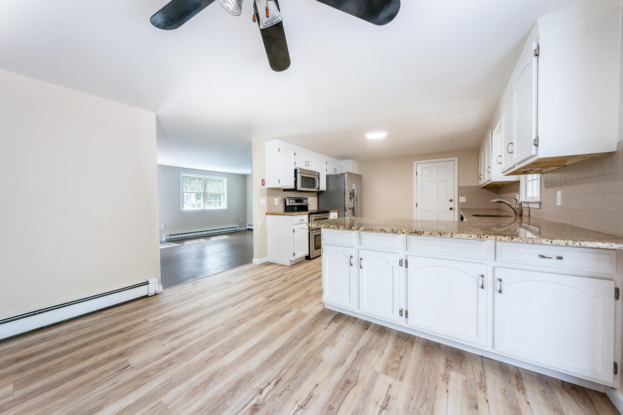 65 Elliott Road Centerville, MA 02632 - Photo 17 of 36 a kitchen with granite countertop a stove a sink and white cabinets with wooden floor