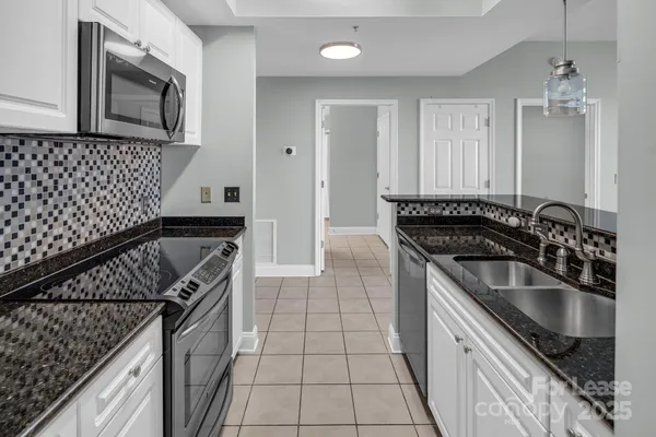 a kitchen with granite countertop a stove sink and microwave