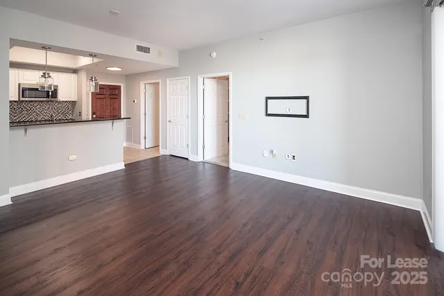 a view of a hallway with wooden floor and a kitchen