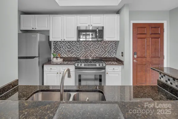 a kitchen with granite countertop a sink stove and refrigerator
