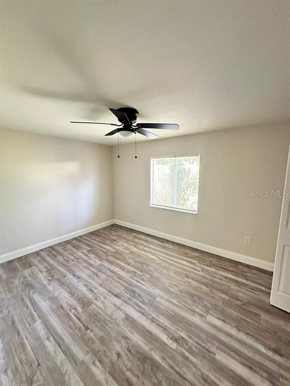 534 Charles Court Orlando, FL 32805 - Photo 4 of 8 an empty room with wooden floor fan and windows