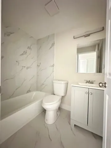 a bathroom with a toilet a sink a mirror and bathtub