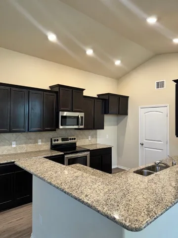 a kitchen with kitchen island granite countertop a sink stove and refrigerator