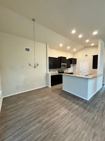 a large kitchen with kitchen island a stove a sink dishwasher a refrigerator and white cabinets with wooden floor