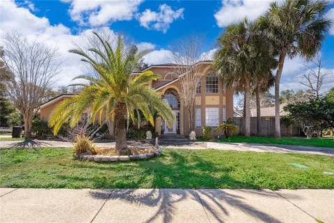 a view of a house with a yard and palm trees