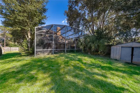 a view of a backyard with wooden fence and a large tree