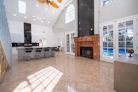 a view of a kitchen with stainless steel appliances granite countertop a stove top oven a sink and a living room view