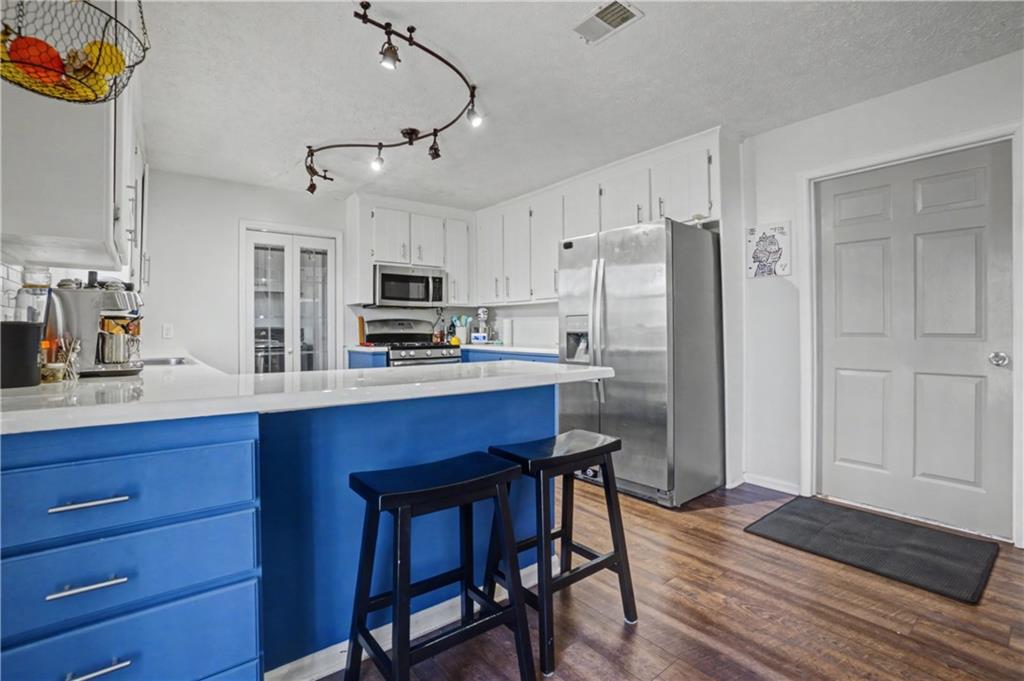 408 Candy Lane Canton, GA 30115 - Photo 10 of 22 a kitchen with stainless steel appliances a refrigerator a stove a sink a dining table and chairs with wooden floor