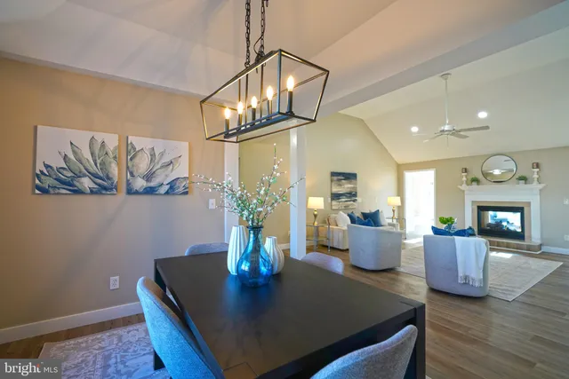a dining room with wooden floor a chandelier a glass table and chairs