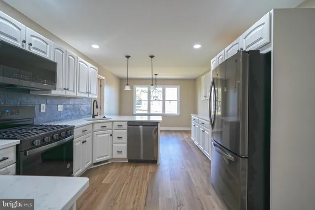 a kitchen with stainless steel appliances granite countertop a stove a sink dishwasher a refrigerator and a microwave oven with wooden floor