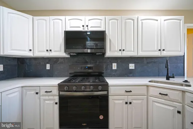 a kitchen with white cabinets and black appliances