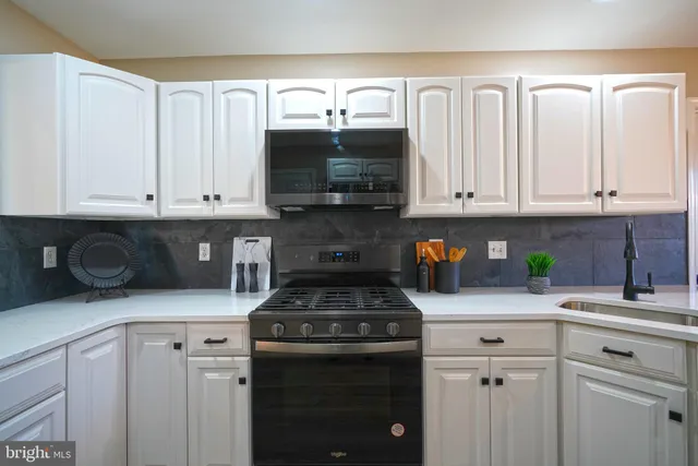 a kitchen with kitchen island granite countertop a sink a center island a stove and a cabinets