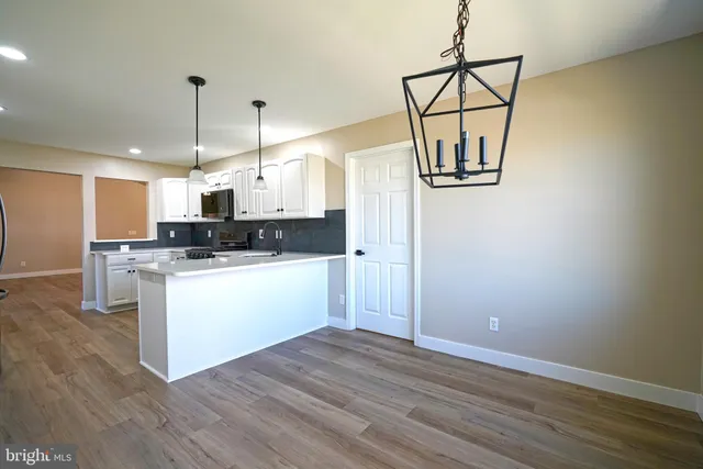 a kitchen with stainless steel appliances granite countertop a refrigerator a stove a microwave and white cabinets with wooden floor