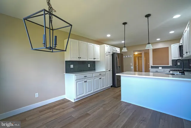 a kitchen with stainless steel appliances granite countertop a sink a stove a refrigerator and wooden floor