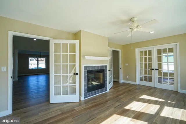 a view of an empty room with wooden floor fireplace and a window