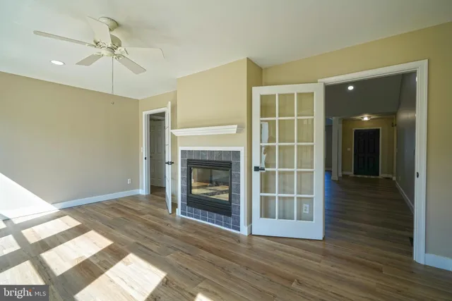 a view of an empty room with wooden floor fireplace and a window