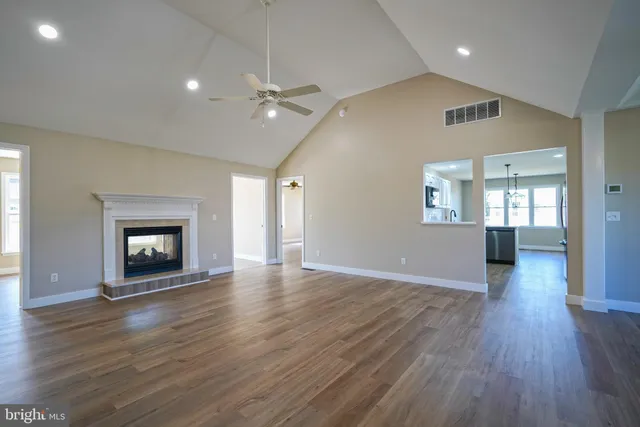 an empty room with wooden floor fireplace and windows