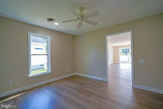 an empty room with wooden floor chandelier and windows