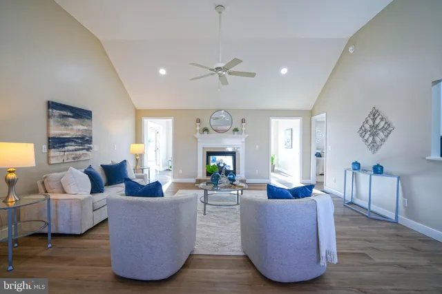 a living room with couches a fireplace and a chandelier with wooden floor