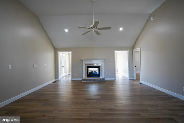 an empty room with wooden floor fireplace and windows