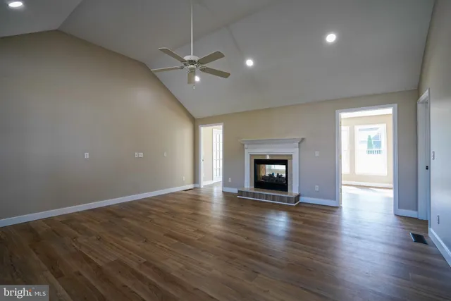 an empty room with wooden floor fireplace and windows