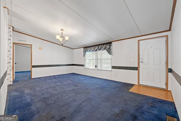 an empty room with wooden floor fireplace and windows