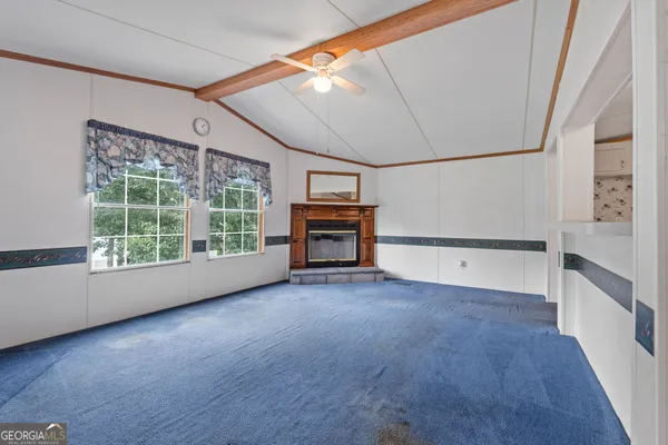 an empty room with wooden floor fireplace and windows