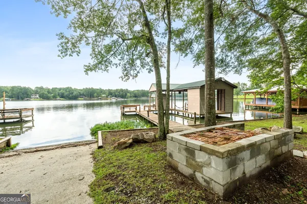 a view of a house with lake and trees in the background