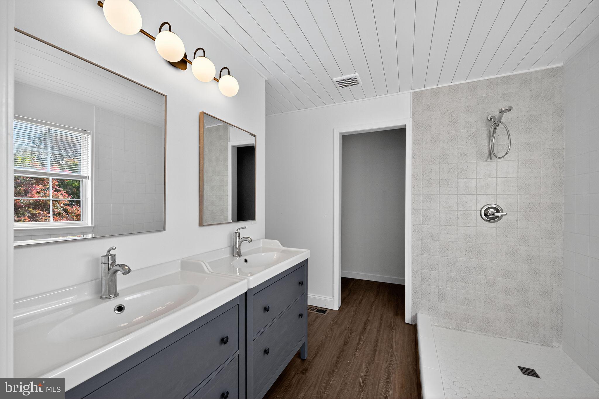 231 Cool Spring Lane Stewartstown, PA 17363 - Photo 22 of 27 a bathroom with a double vanity sink a large mirror and a bathtub