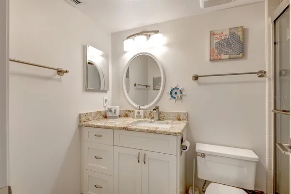 a bathroom with a granite countertop sink toilet and a mirror