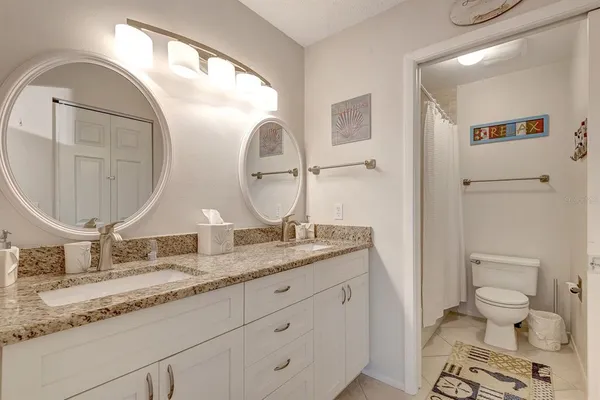a bathroom with a granite countertop toilet a sink and a mirror