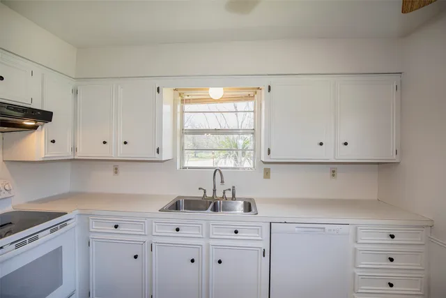 a kitchen with white cabinets and wooden floor