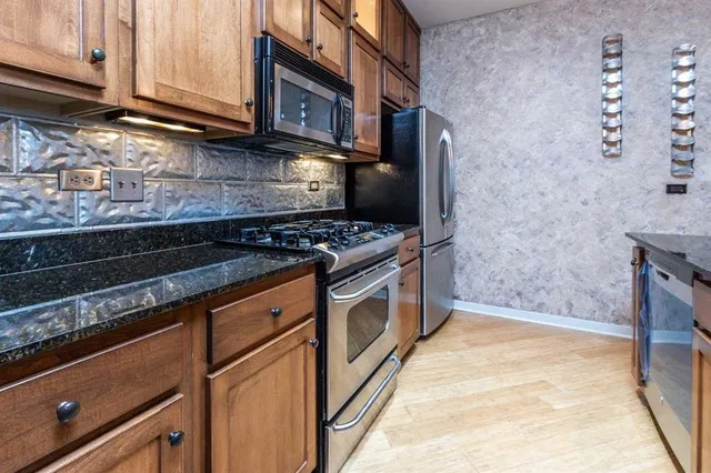 a kitchen with stainless steel appliances granite countertop a stove and a microwave