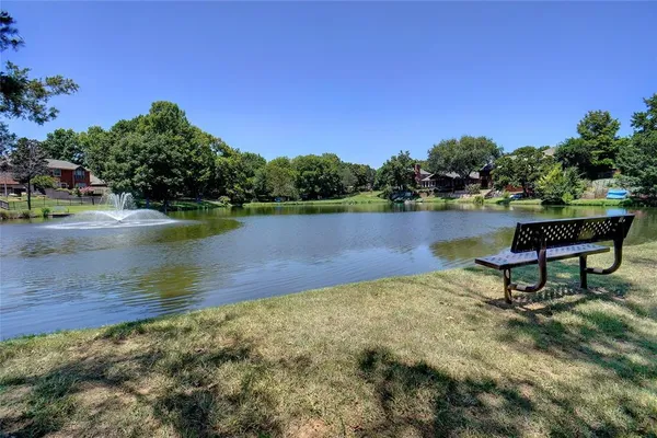 a view of a lake with a bench and trees in the background