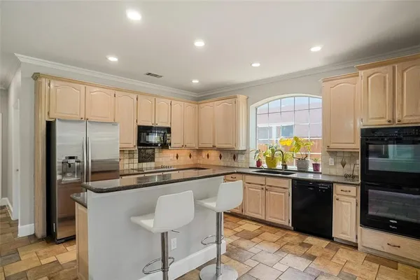 a kitchen with stainless steel appliances granite countertop a sink and a refrigerator