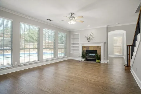 a view of an empty room with wooden floor fireplace and a window
