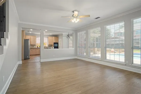 a view of an empty room with a window and kitchen view