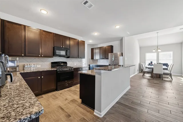 a kitchen with stainless steel appliances granite countertop wooden cabinets a stove top oven a sink and dishwasher