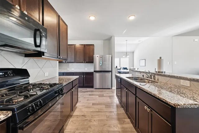 a kitchen with stainless steel appliances granite countertop a stove a sink and a refrigerator